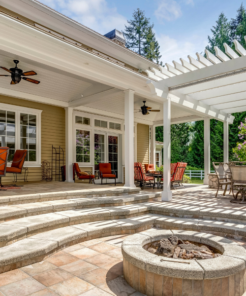 A patio with a fire pit surrounded by chairs