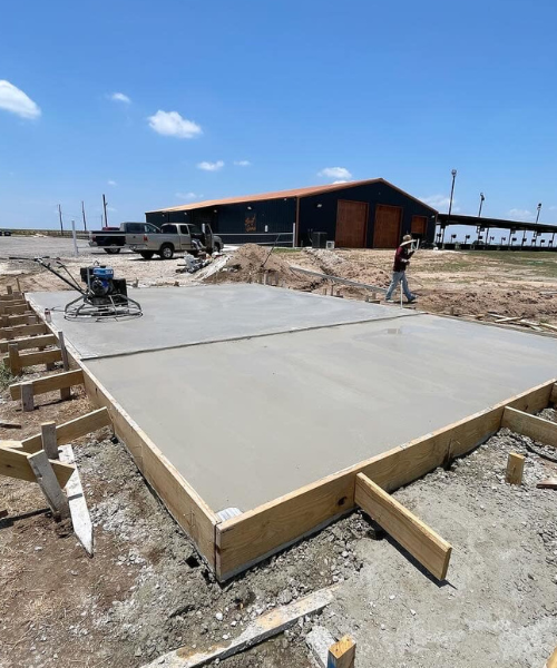 A man walking across a cement slab in the middle of a construction site