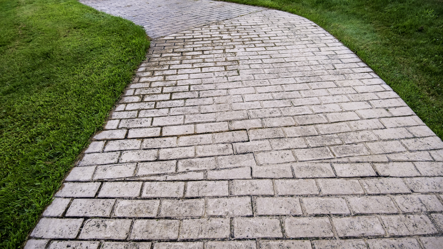 A brick path in a grassy area with a bench in the background